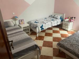 sypialnia z 2 łóżkami i podłogą wyłożoną szachownicą w obiekcie Lina confort a tanger w mieście Tanger