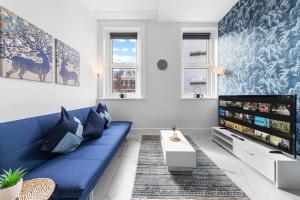 a living room with a blue couch and a tv at Modern 2 Bedroom Flat - Near Primrose Hill, Camden Market, Regent's Park - Good Links to Kings Cross, Euston, Finchley Road Station - NW3 London in London