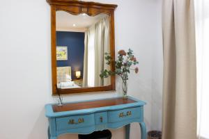 uma cómoda azul com um espelho e um vaso com flores em Elegant 4 bedroom, Maidstone house by Light Living Serviced Accommodation em Maidstone