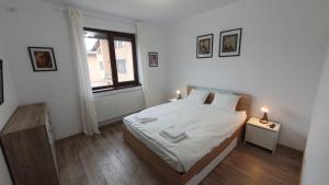 a white bedroom with a bed and a window at MRȘ House 2 in Bucharest