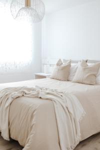 een witte slaapkamer met een groot bed met witte lakens en kussens bij Casa da Sereia in Leiria