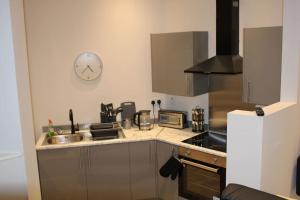 uma cozinha com um lavatório e um relógio na parede em Glossop Hive em Glossop