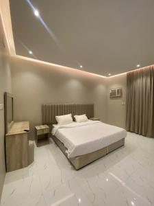 ein Schlafzimmer mit einem großen weißen Bett und einem TV in der Unterkunft شقق نور سين in Al-'Ula