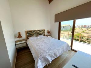 a white bedroom with a bed and a large window at NAUTICA CHINCHA Casa con Piscina frente al mar in Casa Blanca