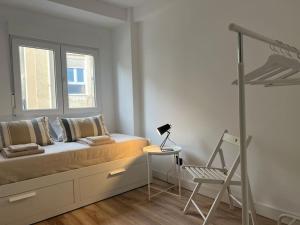 1 dormitorio con cama, ventana y silla en Apartamento en Santander con vistas al mar, en Santander
