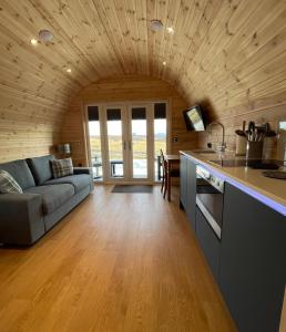 eine Küche und ein Wohnzimmer mit einem Sofa und einem Tisch in der Unterkunft Stoer Pods - Suilven Pod in Lochinver