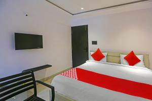 een slaapkamer met een bed met rode kussens en een televisie bij Botcha Convection in Visakhapatnam