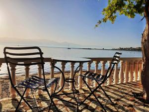 duas cadeiras e uma mesa sobre uma cerca com a água em Tropical Beach A1 em Kalamaki