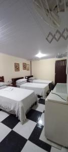 Habitación con 3 camas en un suelo blanco y negro a cuadros en KzaZenDF Hostel CamaeCafé AsaSul, en Brasilia