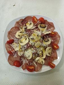 un plato de comida con carne y verduras en una mesa en B&B I tre gatti, en Frassinello Olivola