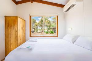 Un dormitorio con una gran cama blanca y una ventana en BIG4 Naracoorte Holiday Park, en Naracoorte