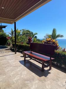 un banco de madera sentado en un patio cerca del océano en Villa Del Mar 1 Spectacular ocean view!, en Dominical