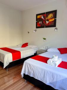 - une chambre avec 2 lits dotés de draps rouges et blancs dans l'établissement Residencial Marina House, à Tarapoto