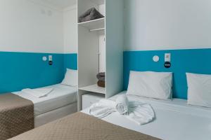 two beds in a room with blue and white at Zuza Slim Suítes in Maceió
