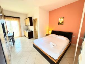 um quarto com uma cama com lençóis brancos e paredes cor-de-laranja em Ksamil Harmony Studios em Ksamil