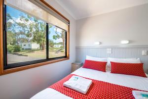 a bedroom with a bed with red pillows and a window at BIG4 Naracoorte Holiday Park in Naracoorte