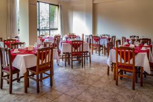a restaurant with tables and chairs with red and white tablecloths at Hotel Oblitas in Cochabamba