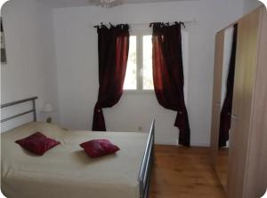 Appartement moderne et calme à Sartène en Corse du Sud في سارتين: غرفة نوم بها سرير مع وسائد حمراء ونافذة