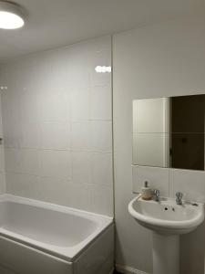 a white bathroom with a sink and a tub and a toilet at Cosy 2 Bedroom Apartment with Parking by Cloud Suites in Manchester