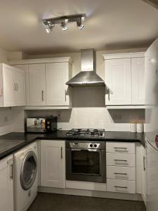 a kitchen with white cabinets and a stove top oven at Cosy 2 Bedroom Apartment with Parking by Cloud Suites in Manchester
