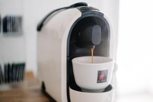 a coffee maker is pouring coffee into a cup at GästeHaus am Flughafen Düsseldorf in Düsseldorf