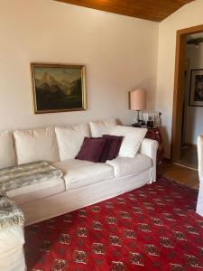 um sofá branco numa sala de estar com um tapete vermelho em Attico con vista sulle Tofane em Maion