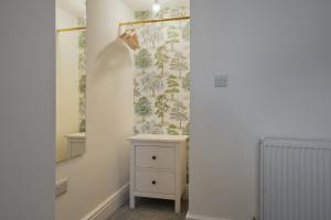 a hallway with a dresser and a wallpaper with trees at Luxury Sheffield Apartment - Your Ideal Home Away From Home in Stannington