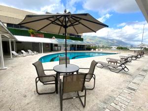 een tafel en stoelen met een parasol naast een zwembad bij Suite. HotelCCT in Caracas
