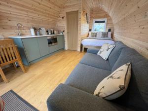 a living room with a blue couch and a kitchen at Stoer Pods - Quinag Pod in Lochinver