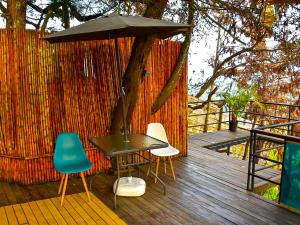 a table and chairs on a deck with an umbrella at Omghat Glamping - Domo Ganesha in El Peñol