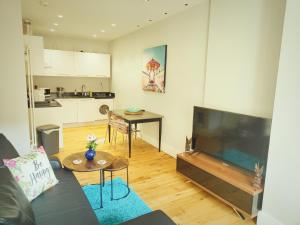 een woonkamer met een bank, een tv en een tafel bij Modern Central Brighton patio flat - free parking! in Brighton & Hove