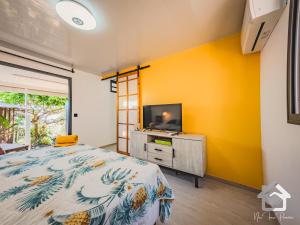 帕皮提的住宿－Airport Pamatai Studio，一间卧室设有黄色的墙壁、一张床和一台电视机。