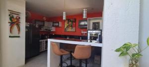 a kitchen with red walls and a counter and stools at Casa Piscis Spa in Taganga
