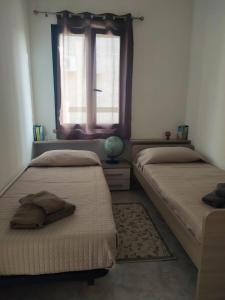 two beds in a room with a window and a rug at Casa Adele in San Sperate