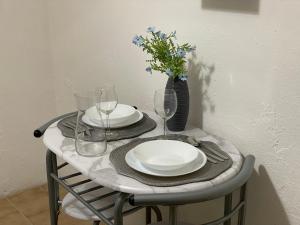 a table with plates and glasses and a vase with flowers at Blue Iris Home in Sanremo