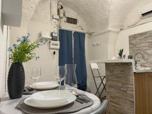 uma sala de jantar com uma mesa com 2 pratos e copos de vinho em Blue Iris Home em Sanremo