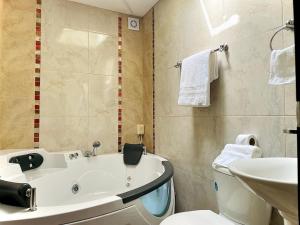 ein Badezimmer mit einer Badewanne, einem WC und einem Waschbecken in der Unterkunft Departamento con jacuzzi, balcón, lavadora y garage in Ambato