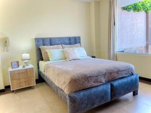 a bedroom with a blue bed and a window at Departamento con jacuzzi, balcón, lavadora y garage in Ambato
