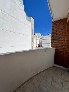 uma varanda com uma parede branca e um edifício de tijolos em Departamento Luminoso en Nueva Cordoba em Córdoba
