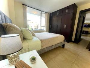 1 dormitorio con 1 cama y 1 mesa con lámpara en Departamento con jacuzzi, balcón, lavadora y garage, en Ambato