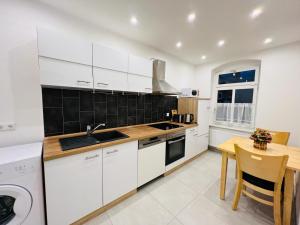 cocina con armarios blancos y mesa de madera en Twenty Five Apartment, en Heidenau