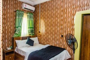 a small bedroom with a bed and a fan at E45 Hotels and Suites in Owerri