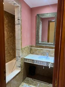 een badkamer met een wastafel, een bad en een spiegel bij Appartement des palmiers avec piscine in Marrakesh