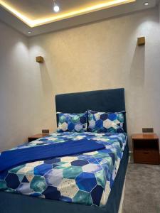 een slaapkamer met een bed met een blauw dekbed bij Appartement des palmiers avec piscine in Marrakesh