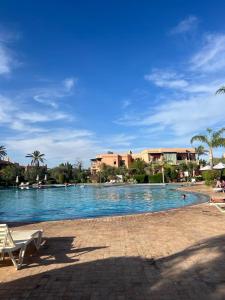 a large swimming pool with palm trees and buildings at Appartement des palmiers avec piscine in Marrakech