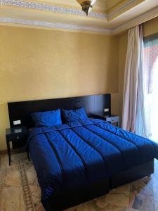 een bed met een blauw dekbed in een slaapkamer bij Appartement des palmiers avec piscine in Marrakesh
