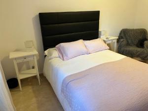 a bedroom with a bed with a black headboard and a chair at Casa Galiana. in Argés