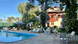 a patio with chairs and a pool and a house at The Helvetia Polo Villa in Indaiatuba