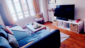 ein Wohnzimmer mit einem blauen Sofa und einem TV in der Unterkunft appartement cosy Asnières-sur-Seine in Asnières-sur-Seine