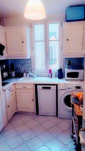 eine Küche mit weißen Schränken und einem Geschirrspüler in der Unterkunft appartement cosy Asnières-sur-Seine in Asnières-sur-Seine